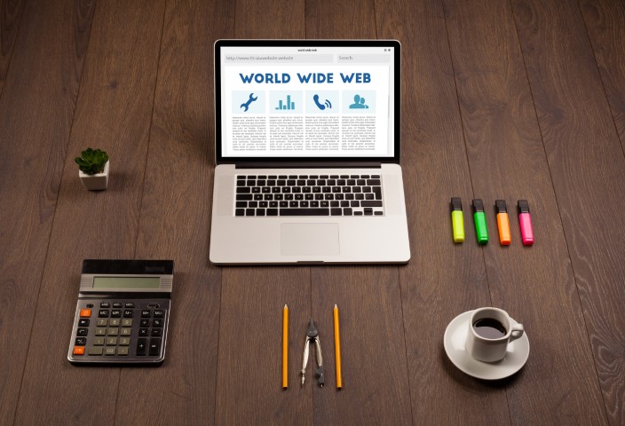 Laptop és irodai eszközök egy rendezett weboldaltervezési munkafelületen